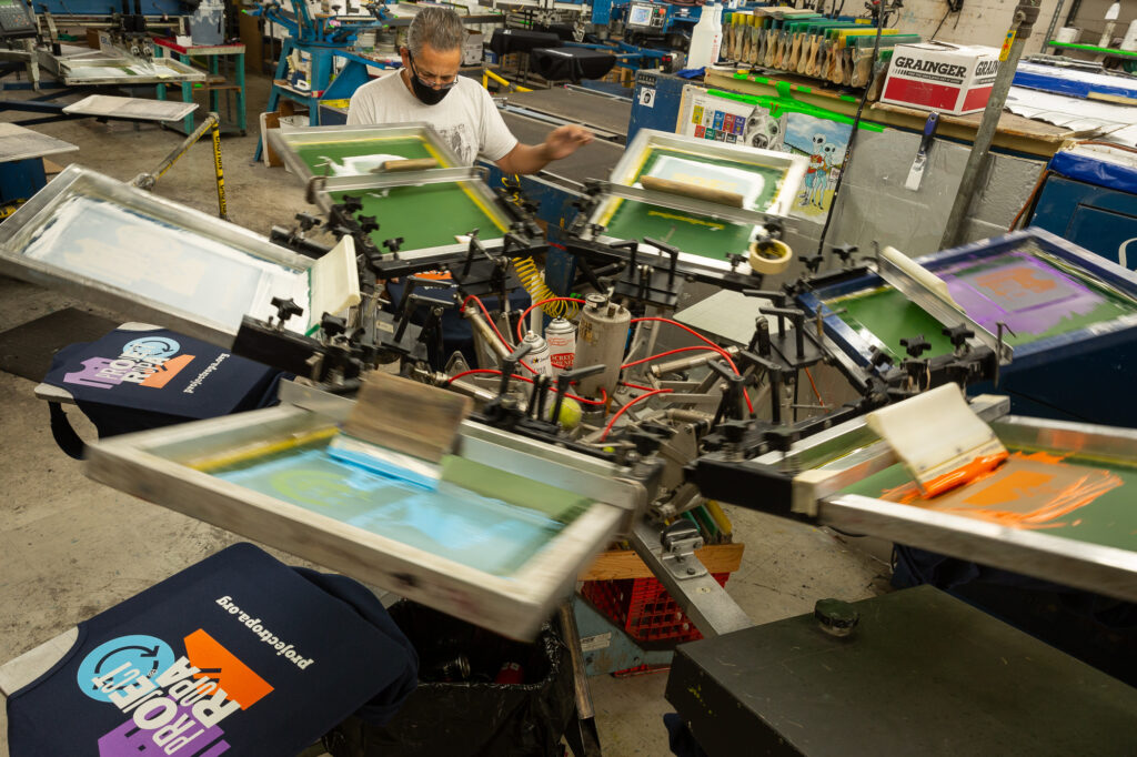 A screen printer operates one of Imprint Revolution's presses.