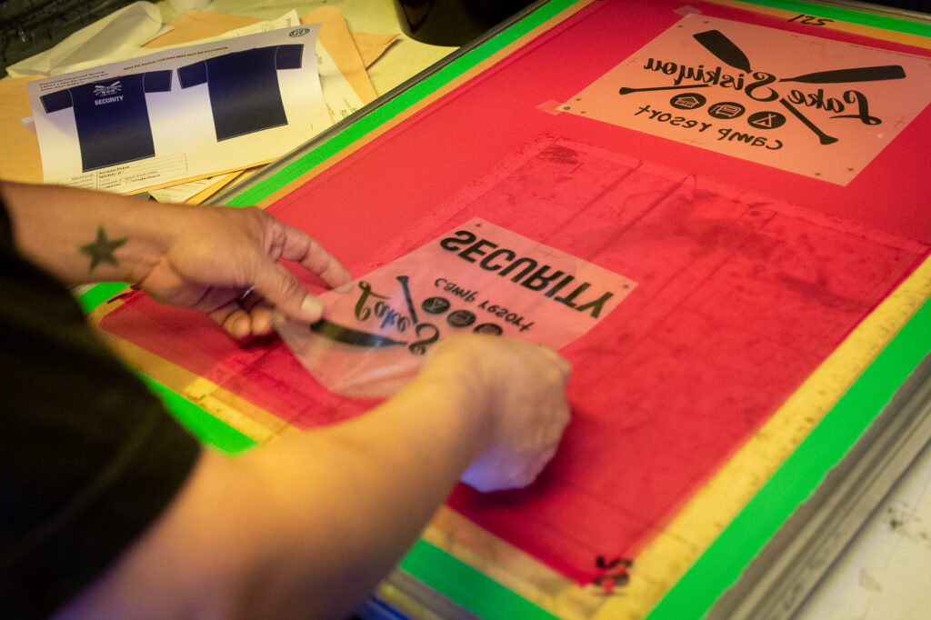 A screen printer carefully places the design on the photo-sensitive screen.