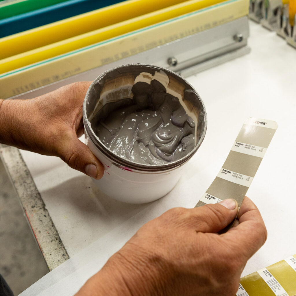 A member of the screen printing team matches ink color to a Pantone swatch.