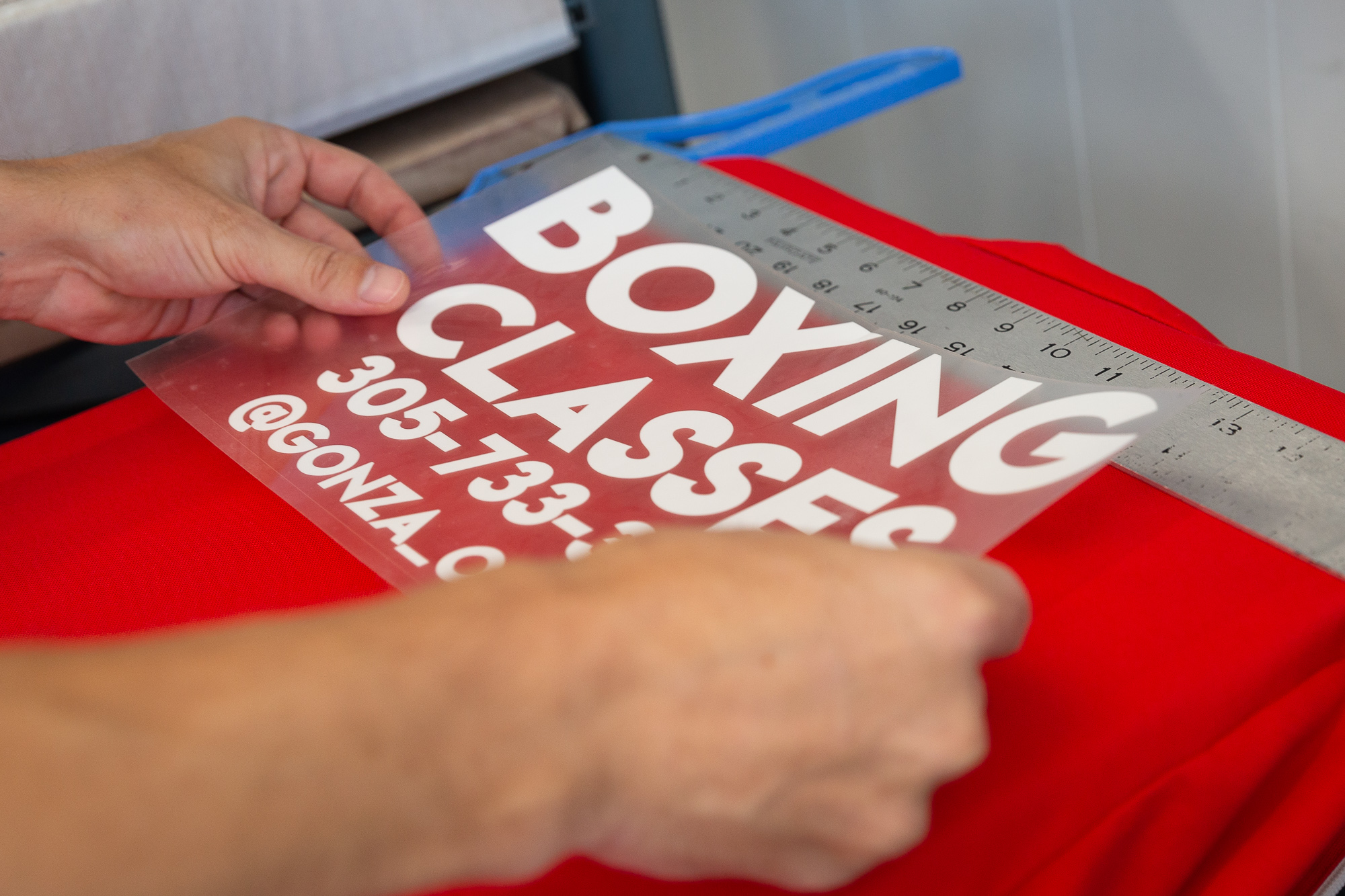 An employee places a vinyl transfer on a garment.