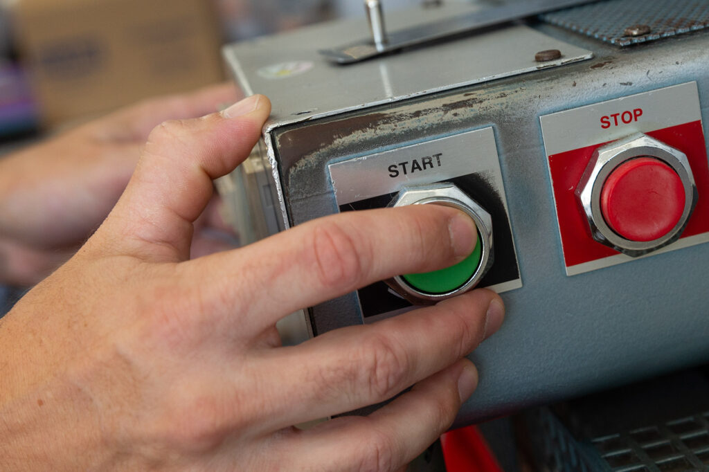 A man presses the start button on a heat press machine.