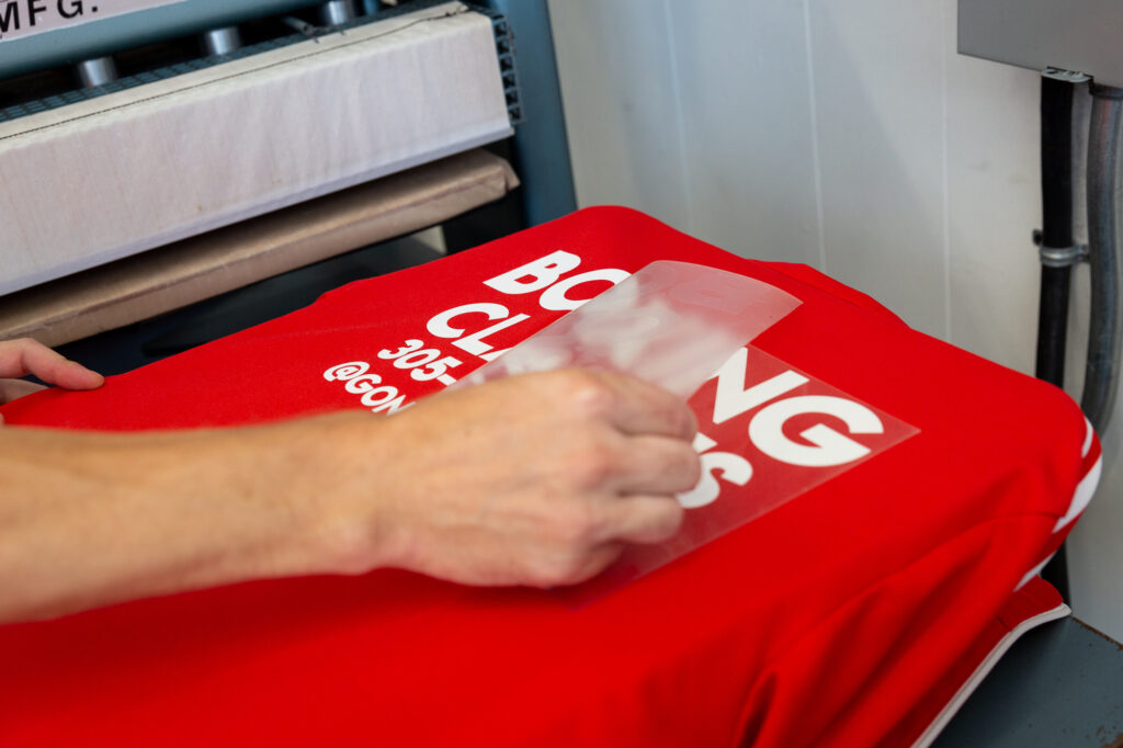 An employee removes the backing material from a vinyl transfer.