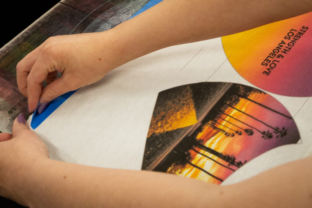 An employee places fabric on the direct-to-garment (DTG) printer.