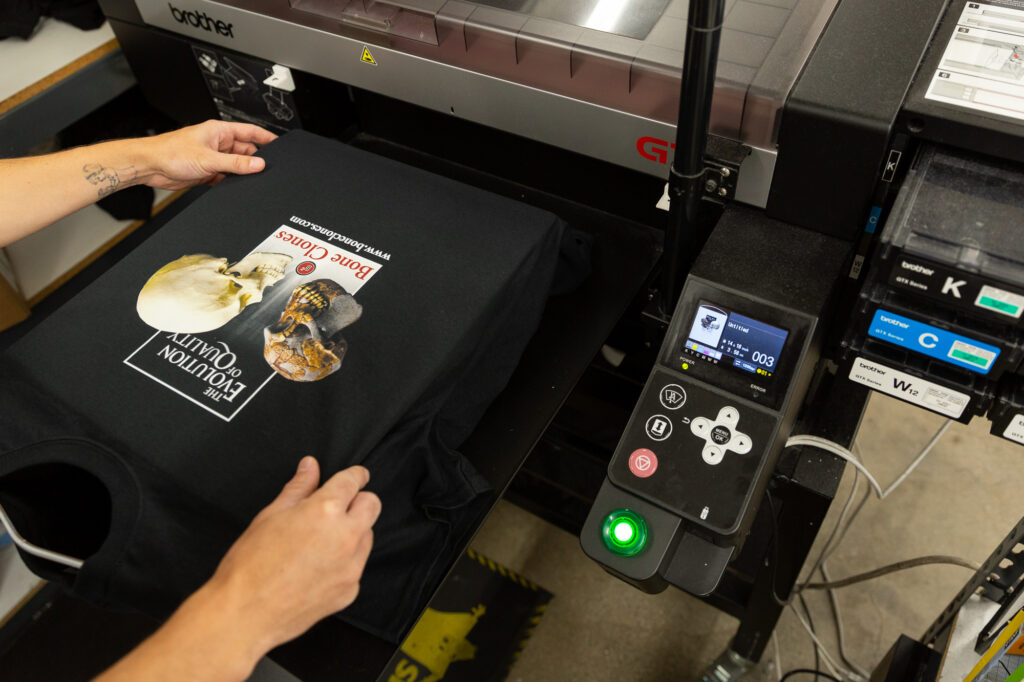 An employee adjusts a garment on the Direct-to-Garment (DTG) printer.