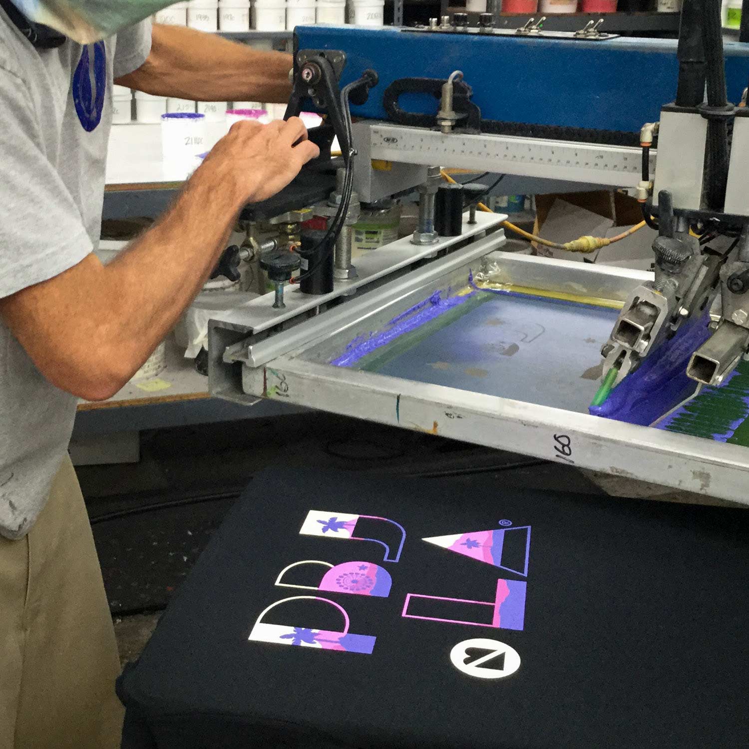 A screen printing press operator creates a custom t-shirt.